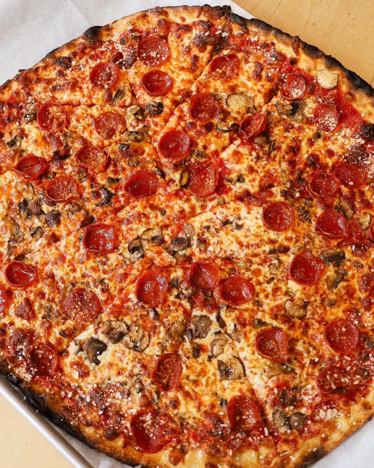 Overhead view of a pepperoni and mushroom apizza with charred crust