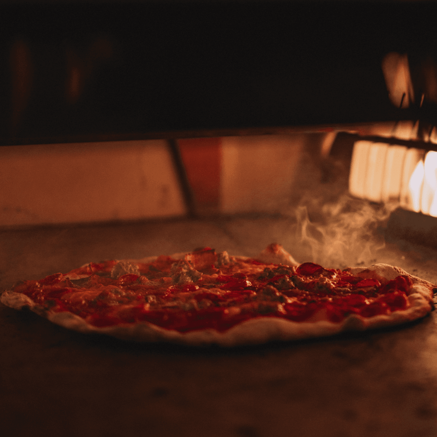 Apizza cooking in a hot oven with steam rising